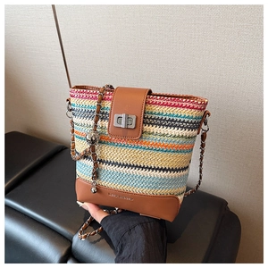 Close-up of colorful woven bucket bag featuring brown leather trim and metal twist lock