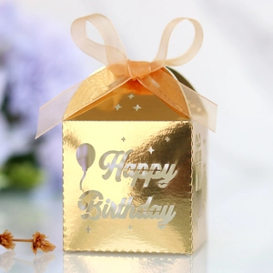 Golden birthday gift box featuring hollowed Happy Birthday text and silk ribbon bow