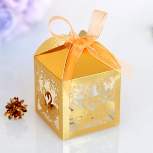 Close-up of golden laser-cut swan favor box with elegant satin ribbon for weddings