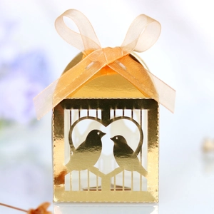 Détail de la boîte à bonbons dorée découpée au laser avec oiseaux et ruban d'organza