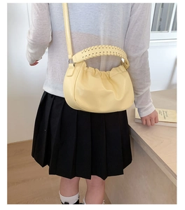 Detail view of light yellow dumpling bag with ruched design and woven handle