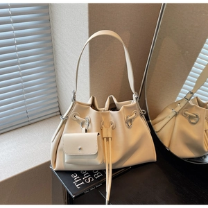 Close-up of cream leather bucket bag with drawstring closure and mini square coin purse