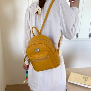 Détail du mini sac à dos jaune en cuir grainé avec une chaîne de perles arc-en-ciel