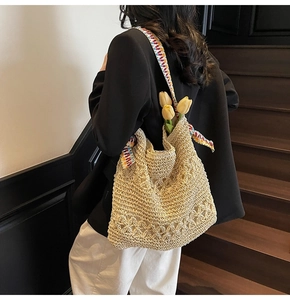 Detail of beige straw tote bag featuring intricate openwork weave and colorful patterned strap