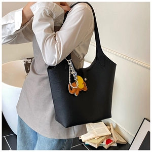 Close-up of black pebble leather tote bag featuring a decorative elephant charm detail