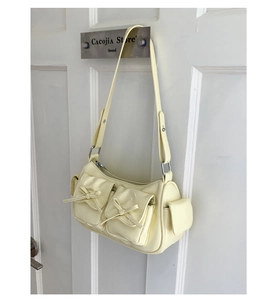 Détail des poches décorées de nœuds sur un sac à bandoulière brillant style Y2K