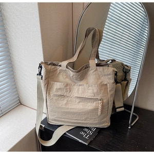 Detail of beige tote bag showing nylon texture and adjustable shoulder strap