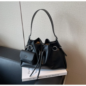 Detailed macro view of black leather drawstring shoulder bag with a mini coin pouch charm