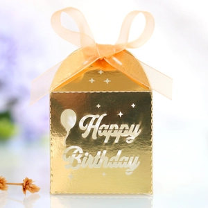 Detailed close-up of golden Happy Birthday favor box with orange ribbon and laser cutouts