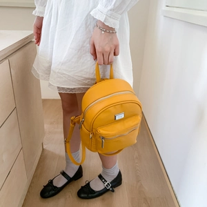 Détail d'un mini sac à dos en cuir jaune vif avec des ferrures en argent et bretelles