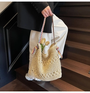 Close-up of beige hollow-out woven tote bag with colorful ribbon strap and tulips
