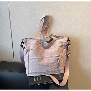 Detail view of pink pleated nylon tote bag with front zipper pocket and side pockets