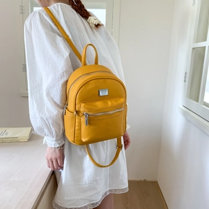Gros plan d'un mini sac à dos en cuir grainé jaune vif avec fermetures éclair argentées