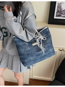 Blue denim tote bag with lace bows and silver leather straps shown on a model