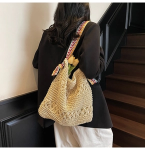 Detail of beige hollow-out woven tote bag featuring a colorful rainbow braided strap