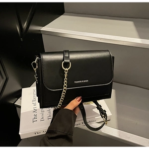 Close-up of black leather crossbody bag with gold chain strap and stylish gold lettering