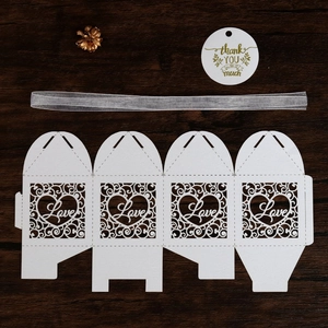 Detail of white laser-cut Love gift box with silver ribbon, tag, and gold flower decoration