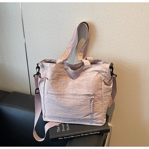 Close-up of pink pleated nylon tote bag with shoulder strap and functional multi-pockets