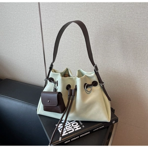 Detailed close-up of a cream white minimalist bucket bag with brown drawstring and shoulder strap