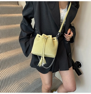 Detail of woven texture on bucket bag with drawstring, tassels and silver chain strap
