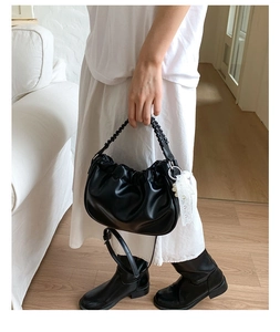Detail of black pleated cloud bag with lace pearl charm and braided handle