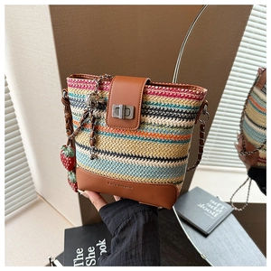 Detail of colorful striped straw bucket bag with leather trim and strawberry charms