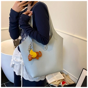 Detail of light blue lychee grain leather tote bag with a cute orange elephant charm