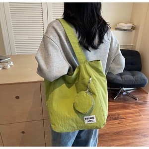 Detail of green canvas tote bag with hanging coin purse and minimalist woven brand label