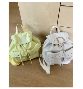 Detail of trendy drawstring backpacks in light green and white with artistic D print