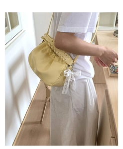 Detail view of yellow ruched cloud bag with woven rope trim and lace bow charm accent