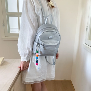 Détail du mini sac à dos argenté en similicuir avec texture litchi et charme perlé