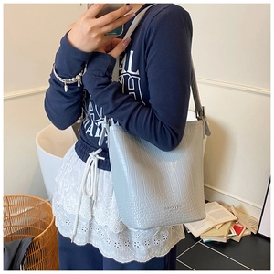 Detail of light blue bucket bag in crocodile embossed leather with adjustable strap