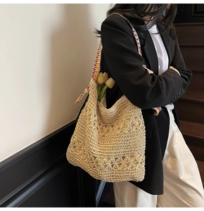 Detail of hand-woven beige tote bag with hollow flower patterns and colorful straps