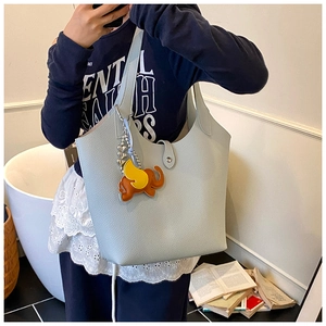 Detail of light blue lychee pattern leather tote bag with elephant charm in home setting