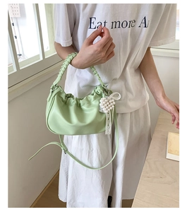 Mint green pleated cloud bag with woven handle and pearl heart charm shown on a model