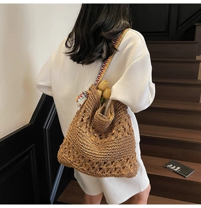 Detail of hand-woven straw tote bag featuring a colorful crochet shoulder strap and large capacity