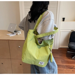 Detail of avocado green nylon tote bag with small detachable pouch and wide strap
