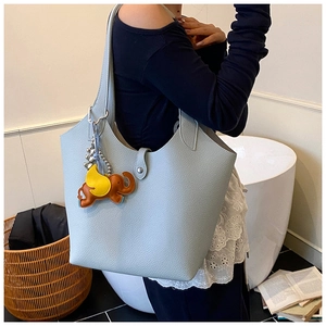 Close-up of light blue leather tote bag with lychee texture and cute elephant charm