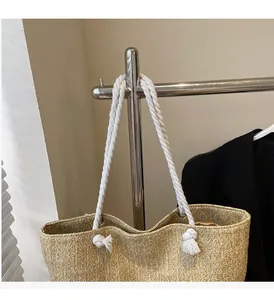Detail of woven straw tote bag with white cotton rope handles and artisanal knotting