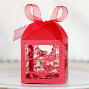 Detailed laser-cut red paper candy box with festive magpie bird pattern and silk ribbon