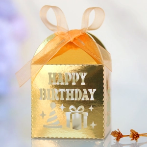 Macro view of golden Happy Birthday candy box with laser-cut hollow letters and satin ribbon