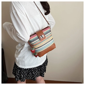 Detail view of woven straw bucket bag with colorful stripes and strawberry charms