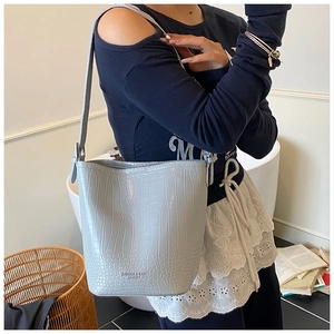 Detail of light blue crocodile texture bucket bag with embossed fashion lettering