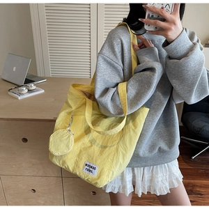 Close-up of bright yellow nylon tote bag with round mini pouch and brand label