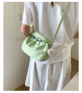 Detail of light green pleated cloud bag with pearl lace charm and woven handle trim