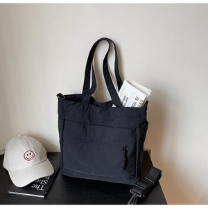 Detail view of black nylon tote bag with utility pockets and detachable shoulder strap