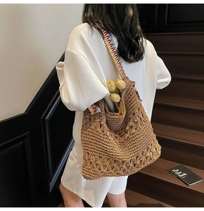 Detail of woven straw tote bag with colorful geometric strap shown from a side view