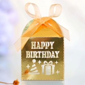 Macro detail of gold laser-cut Happy Birthday candy box with organza bow and stars