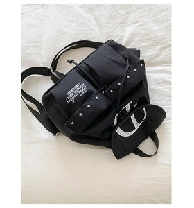 Détail d'un sac à dos en toile noire avec rivets argentés et logo V blanc imprimé