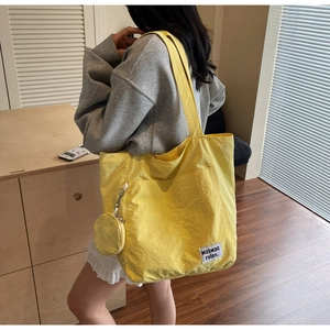 Bright yellow large canvas tote bag with small round coin purse shown on a female model